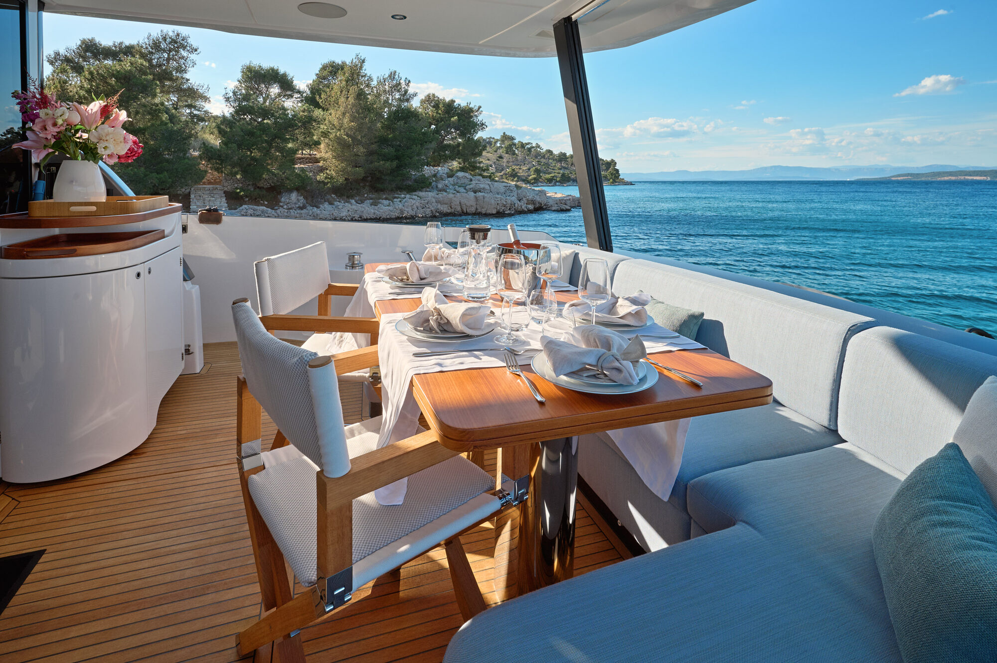 Aft cockpit dining table set with flowers, beside the sea