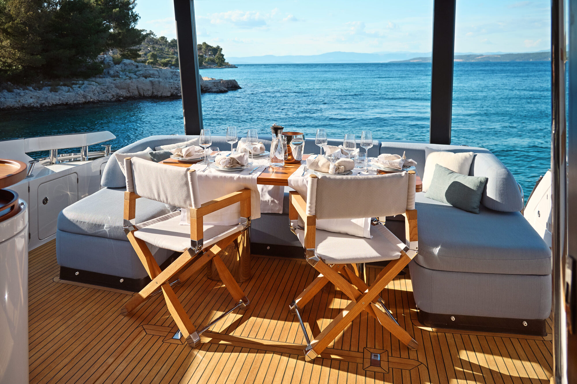 Shaded aft cockpit dining table set for guests beside the sea