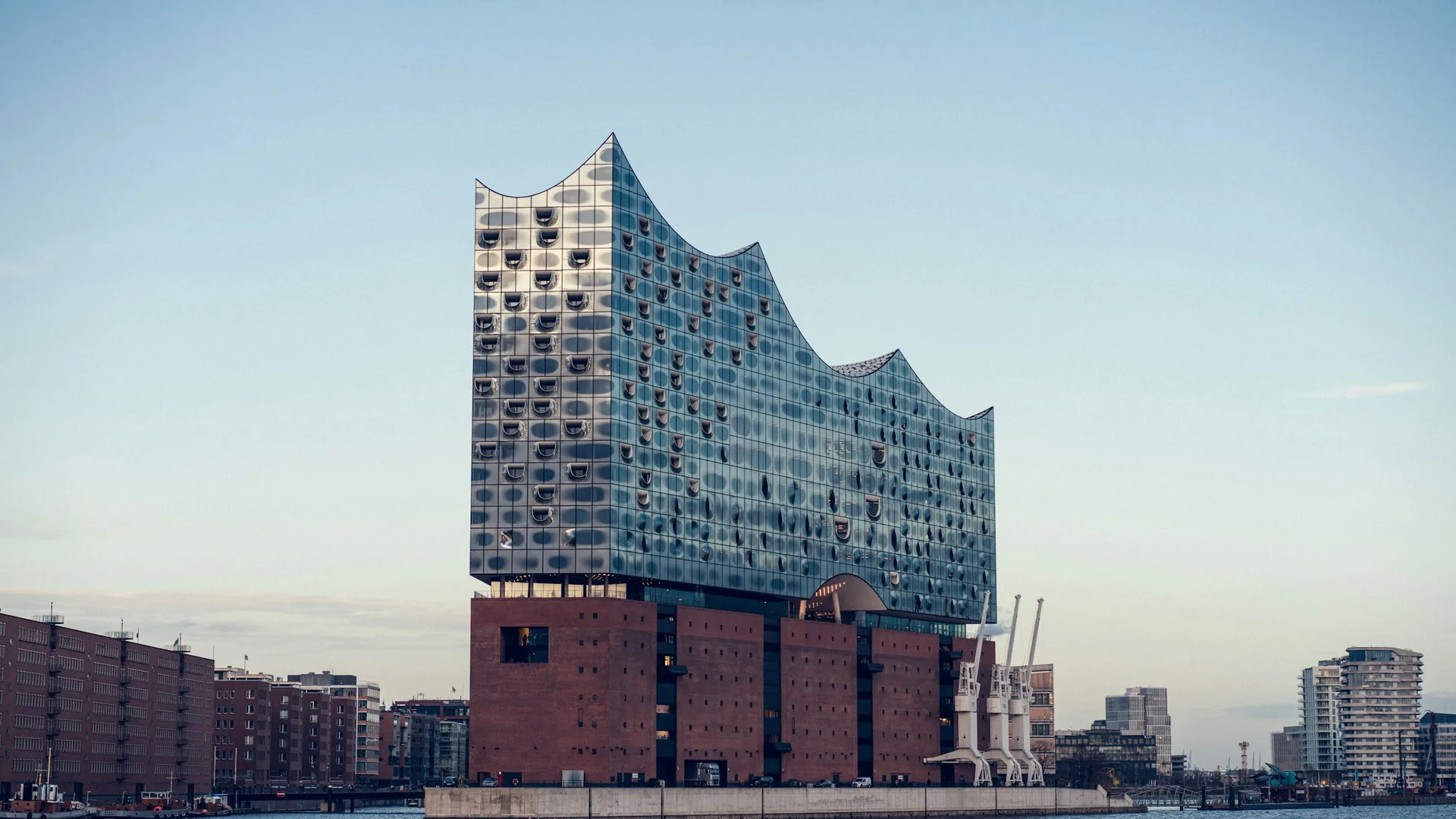 Elbphilharmonie über dem Hafen mit Speicherstadt am Wasser (Foto: Jonas Tebbe / Unsplash)